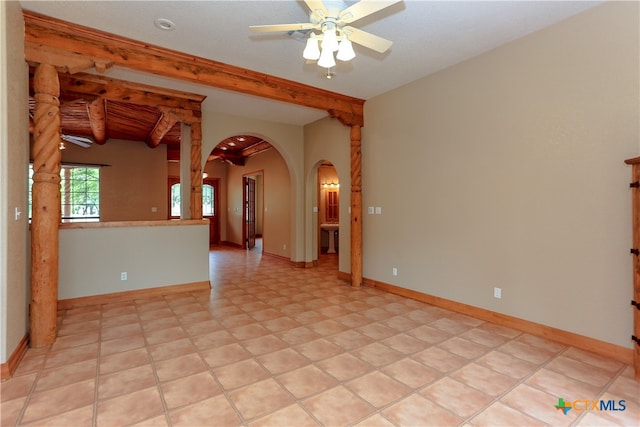 empty room featuring ceiling fan, light tile patterned flooring, and beamed ceiling