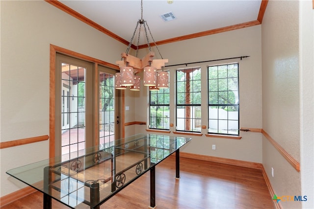 dining space with ornamental molding, hardwood / wood-style flooring, and a chandelier