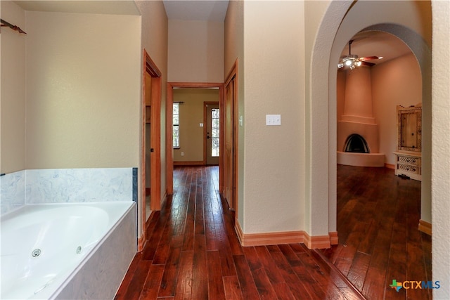 bathroom with a fireplace, hardwood / wood-style flooring, a tub, and ceiling fan