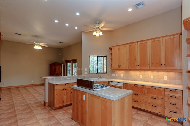 kitchen featuring kitchen peninsula, white dishwasher, light tile patterned floors, backsplash, and a center island