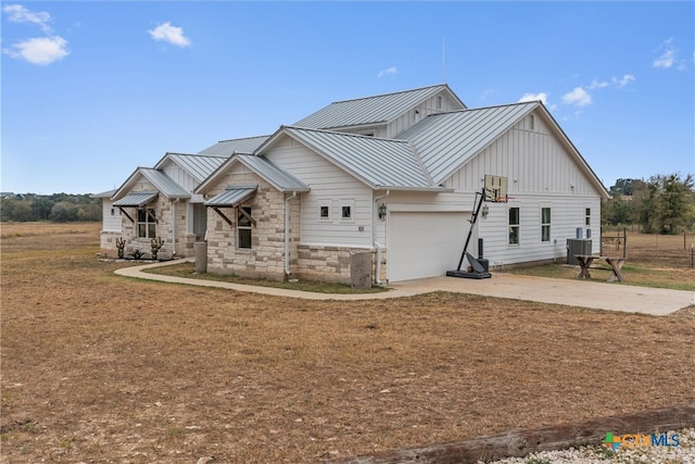 view of front of house featuring cooling unit, a garage, and a front lawn