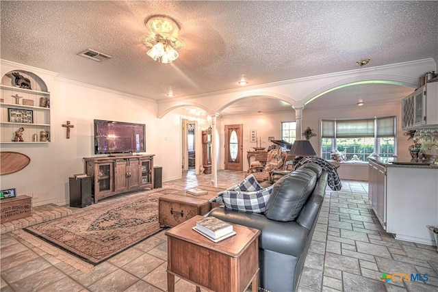 4701 Hickory Rd, Temple, TX 76502 - living area featuring ornate columns, crown molding, a textured ceiling, arched walkways, and stone tile flooring