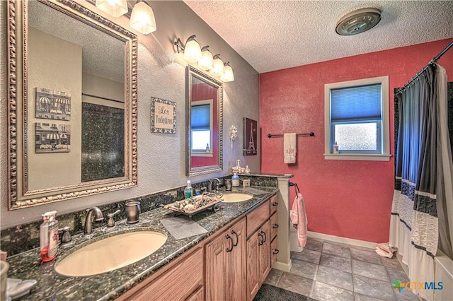 4701 Hickory Rd, Temple, TX 76502 - bathroom with a textured ceiling, a textured wall, double vanity, baseboards, and a shower with shower curtain
