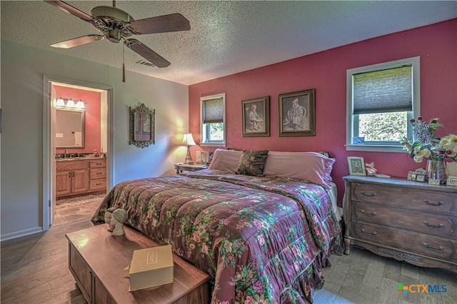 4701 Hickory Rd, Temple, TX 76502 - bedroom featuring multiple windows, a textured ceiling, light wood-style floors, a sink, and ensuite bathroom