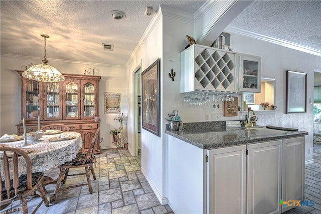 4701 Hickory Rd, Temple, TX 76502 - kitchen featuring a textured ceiling, white cabinets, stone tile floors, crown molding, and decorative light fixtures