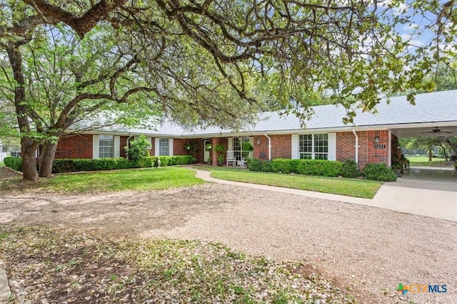 ranch-style home featuring driveway, brick siding, and a front yard