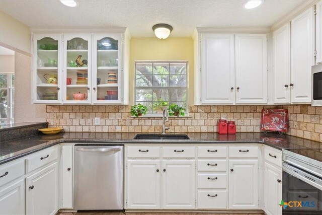 kitchen with decorative backsplash, a sink, white cabinets, appliances with stainless steel finishes, and glass insert cabinets