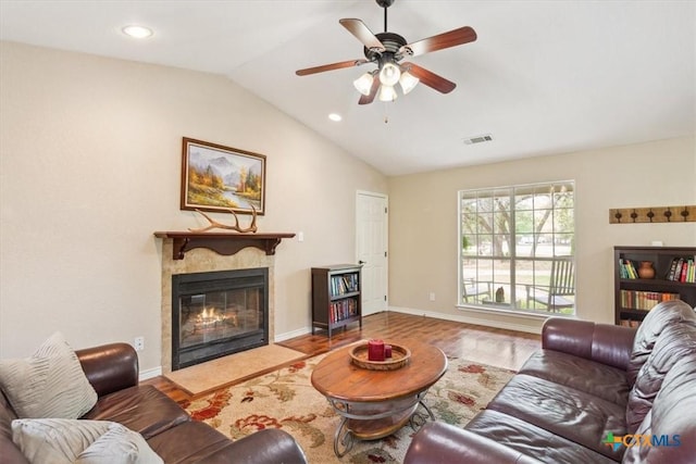 living room featuring vaulted ceiling, wood finished floors, a high end fireplace, visible vents, and ceiling fan