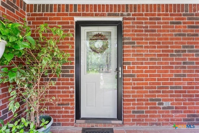 doorway to property featuring brick siding
