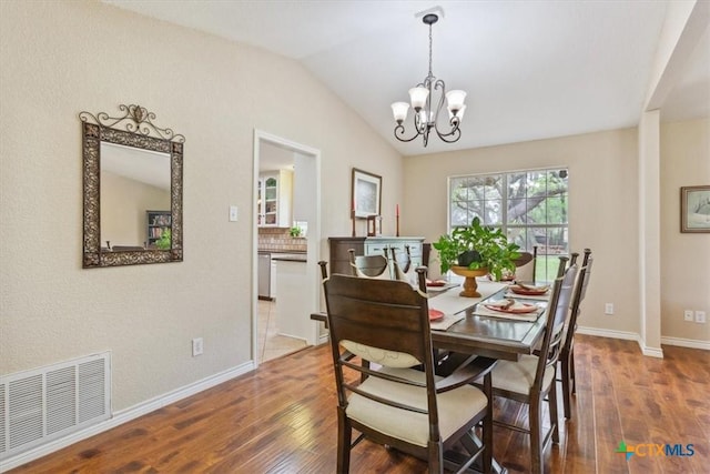 dining room with hardwood / wood-style floors, vaulted ceiling, visible vents, and a chandelier
