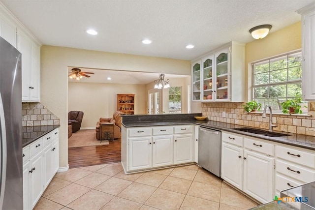 kitchen with a sink, appliances with stainless steel finishes, a peninsula, open floor plan, and light tile patterned floors
