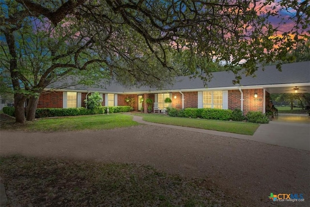 single story home featuring brick siding and a yard
