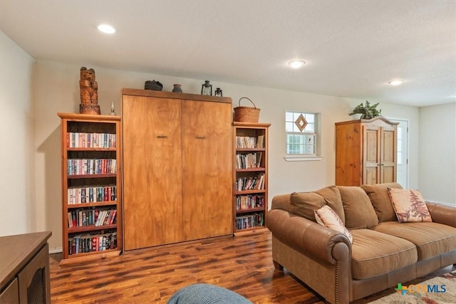living area with dark wood-style flooring and recessed lighting