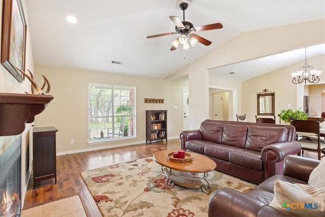 living room with visible vents, baseboards, wood finished floors, lofted ceiling, and ceiling fan with notable chandelier
