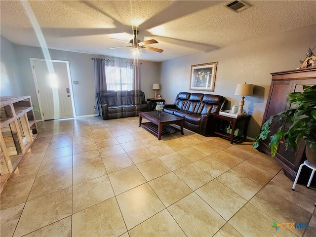 living room featuring ceiling fan, light tile patterned floors, and a textured ceiling