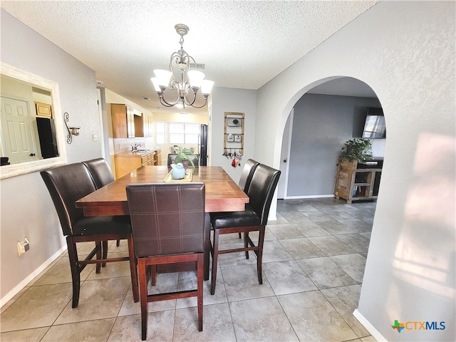 tiled dining room with a chandelier, a textured ceiling, and sink