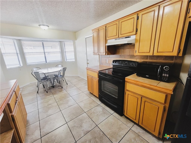 kitchen featuring black appliances, decorative backsplash, light tile patterned flooring, and tile countertops