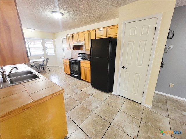 kitchen with tile countertops, black appliances, sink, a textured ceiling, and light tile patterned flooring