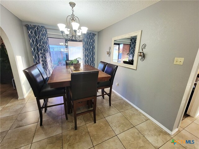 tiled dining space with a notable chandelier and a textured ceiling