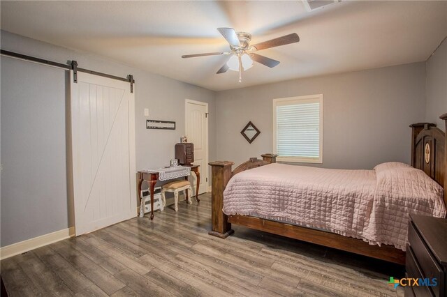 111 Lexington Ln, Victoria, TX 77901 - bedroom with a barn door, baseboards, wood finished floors, and ceiling fan