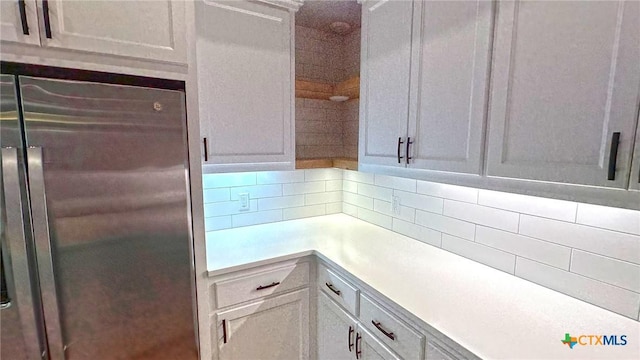 kitchen featuring freestanding refrigerator, light countertops, decorative backsplash, and white cabinetry