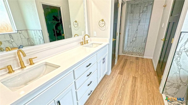 full bath with double vanity, wood finished floors, a sink, and a shower stall