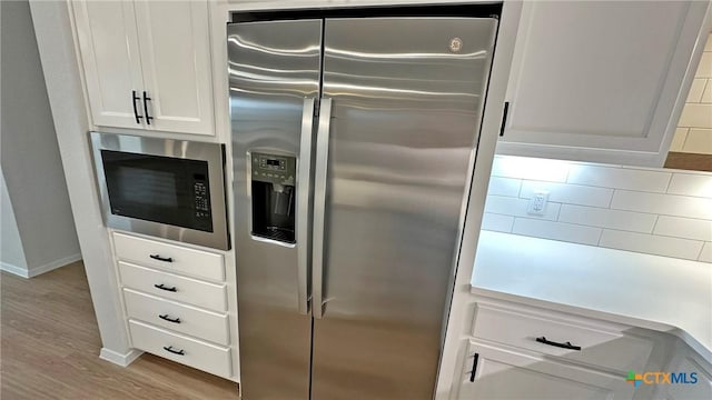 kitchen featuring stainless steel appliances, tasteful backsplash, white cabinets, wood finished floors, and baseboards