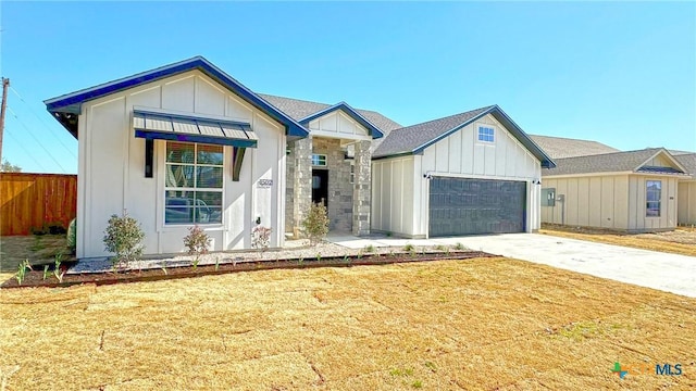 modern inspired farmhouse featuring an attached garage, fence, driveway, a front lawn, and board and batten siding