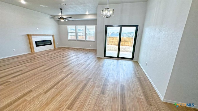 unfurnished living room featuring baseboards, wood finished floors, and a glass covered fireplace