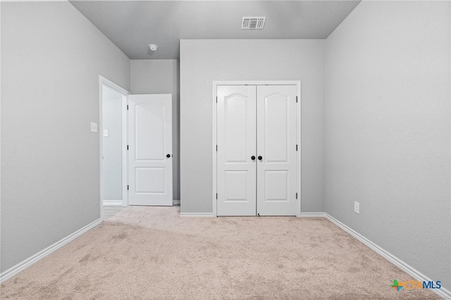 unfurnished bedroom featuring light carpet and a closet