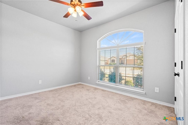 empty room featuring a wealth of natural light, ceiling fan, and light carpet