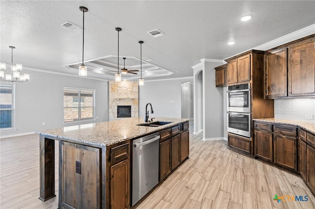 kitchen featuring sink, hanging light fixtures, stainless steel appliances, an island with sink, and a tray ceiling