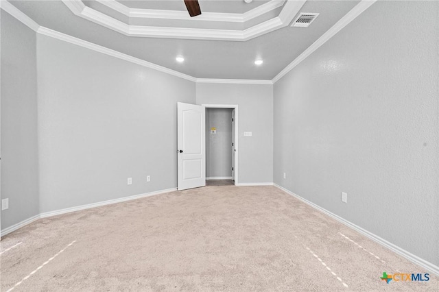 carpeted empty room featuring a raised ceiling and crown molding