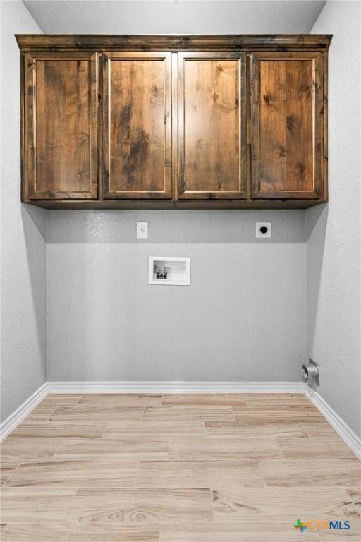 laundry area with hookup for an electric dryer, hookup for a washing machine, light wood-type flooring, and cabinets