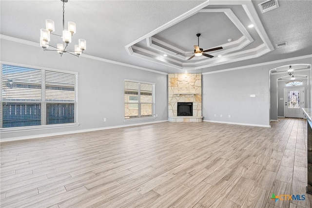 unfurnished living room featuring a fireplace, crown molding, ceiling fan with notable chandelier, and light hardwood / wood-style flooring