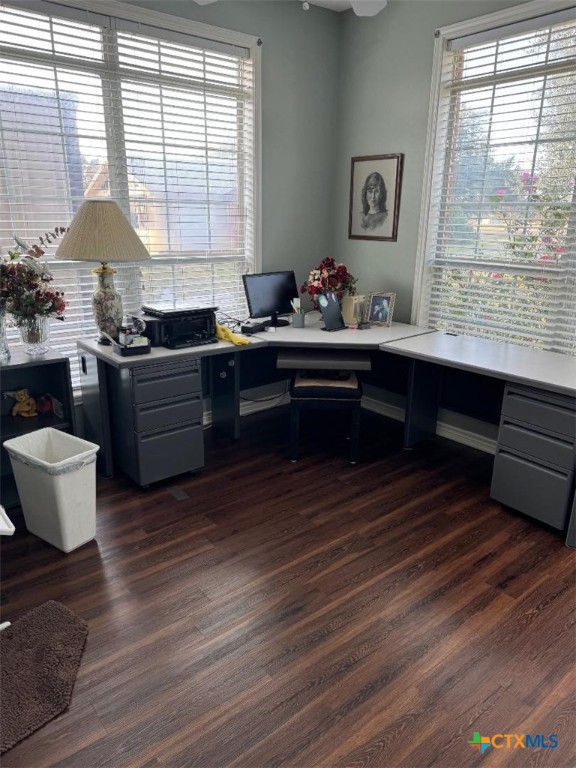 office space with a wealth of natural light, built in desk, and dark hardwood / wood-style floors