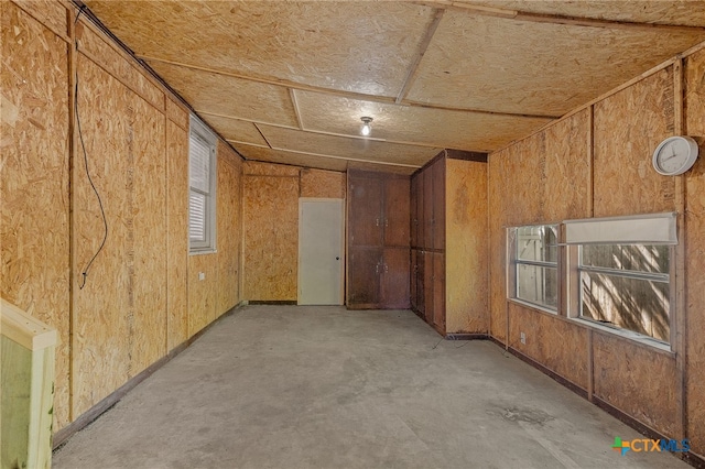 unfurnished room featuring wood walls and vaulted ceiling