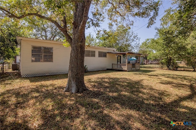 rear view of property with central AC unit and a lawn