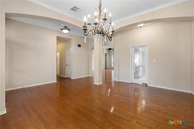 spare room with dark hardwood / wood-style flooring, an inviting chandelier, and ornamental molding