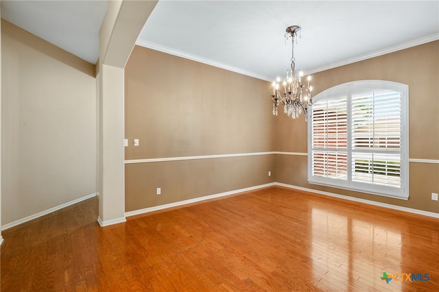 unfurnished room featuring a chandelier, hardwood / wood-style floors, and ornamental molding