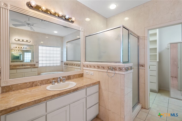 bathroom with vanity, independent shower and bath, tile walls, and tile patterned flooring