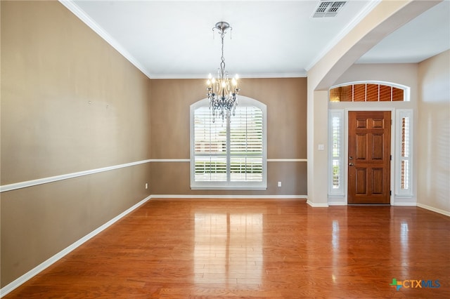 entrance foyer featuring hardwood / wood-style floors, a chandelier, and crown molding