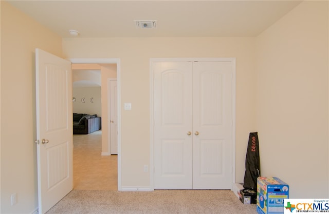 unfurnished bedroom with a closet and light carpet