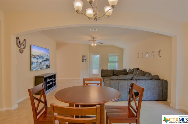 dining area with ceiling fan with notable chandelier, light tile patterned floors, and vaulted ceiling