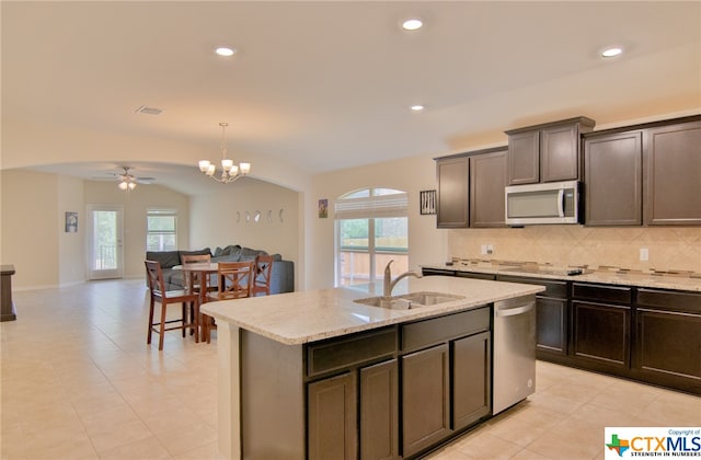 kitchen with stainless steel appliances, a center island with sink, sink, tasteful backsplash, and hanging light fixtures