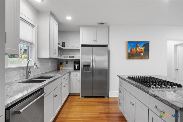 104 E Stayton Ave, Victoria, TX 77901 - kitchen with light stone countertops, open shelves, a sink, appliances with stainless steel finishes, and white cabinetry