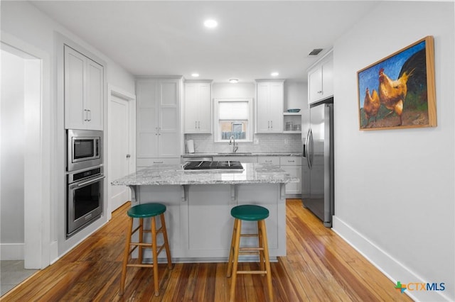 104 E Stayton Ave, Victoria, TX 77901 - kitchen featuring visible vents, a sink, decorative backsplash, appliances with stainless steel finishes, and a kitchen breakfast bar