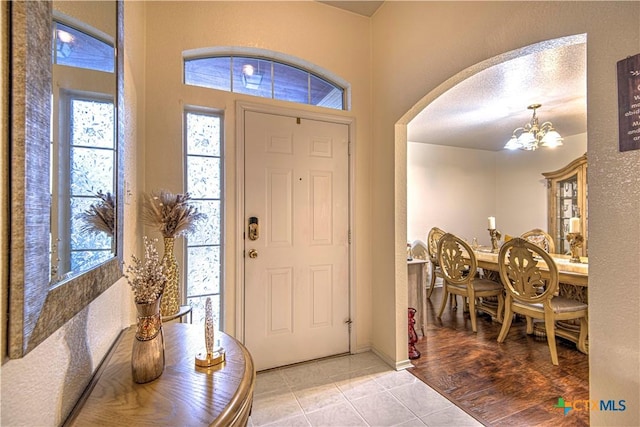 entryway featuring light tile patterned flooring, a wealth of natural light, and a chandelier