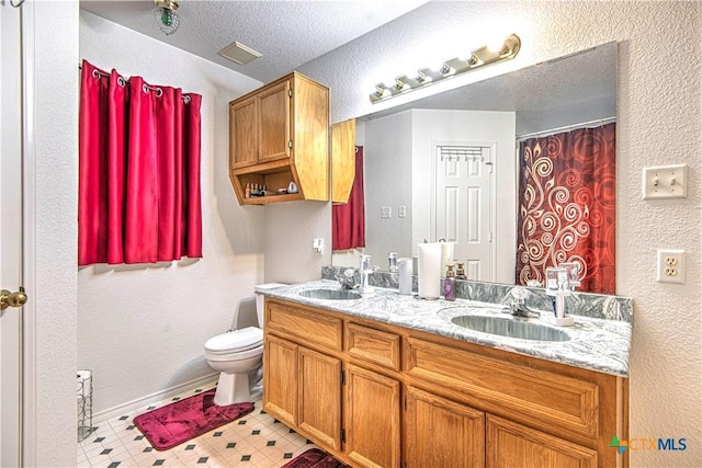 bathroom featuring vanity, a textured ceiling, and toilet