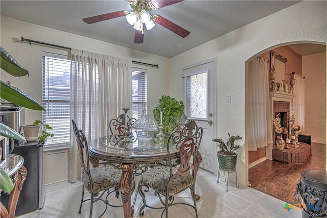 dining room with light tile patterned floors, a fireplace, and a healthy amount of sunlight